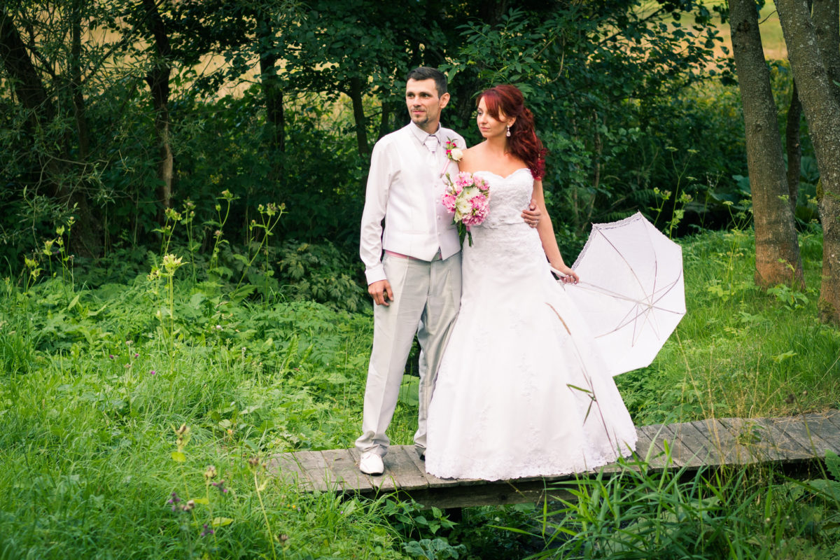 Nevěsta a ženich stojí na mostku, svatební portrét