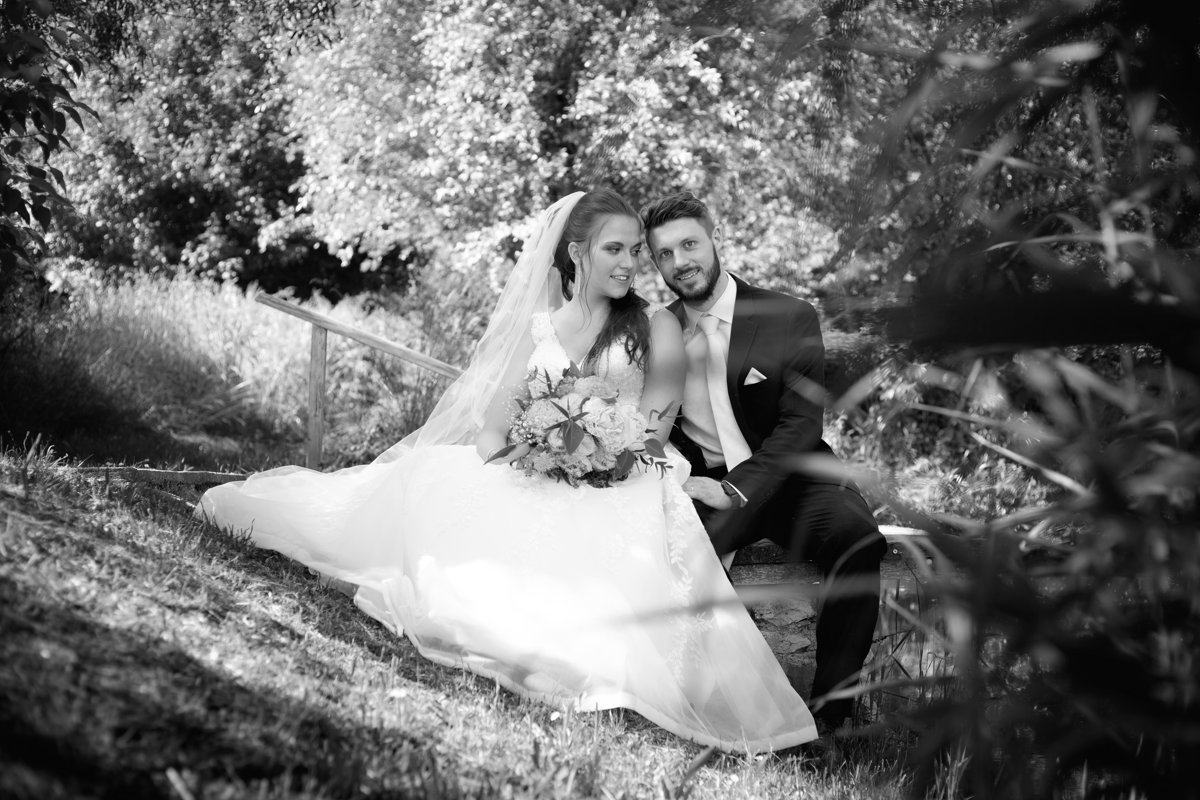 Svatební portrét, nevěsta, ženich, sedí na mole u rybníka