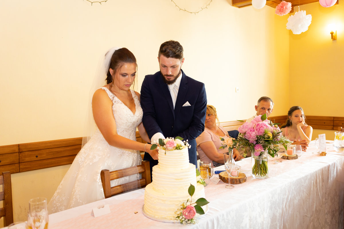Nevěsta se ženichem zakrojují svatební dort