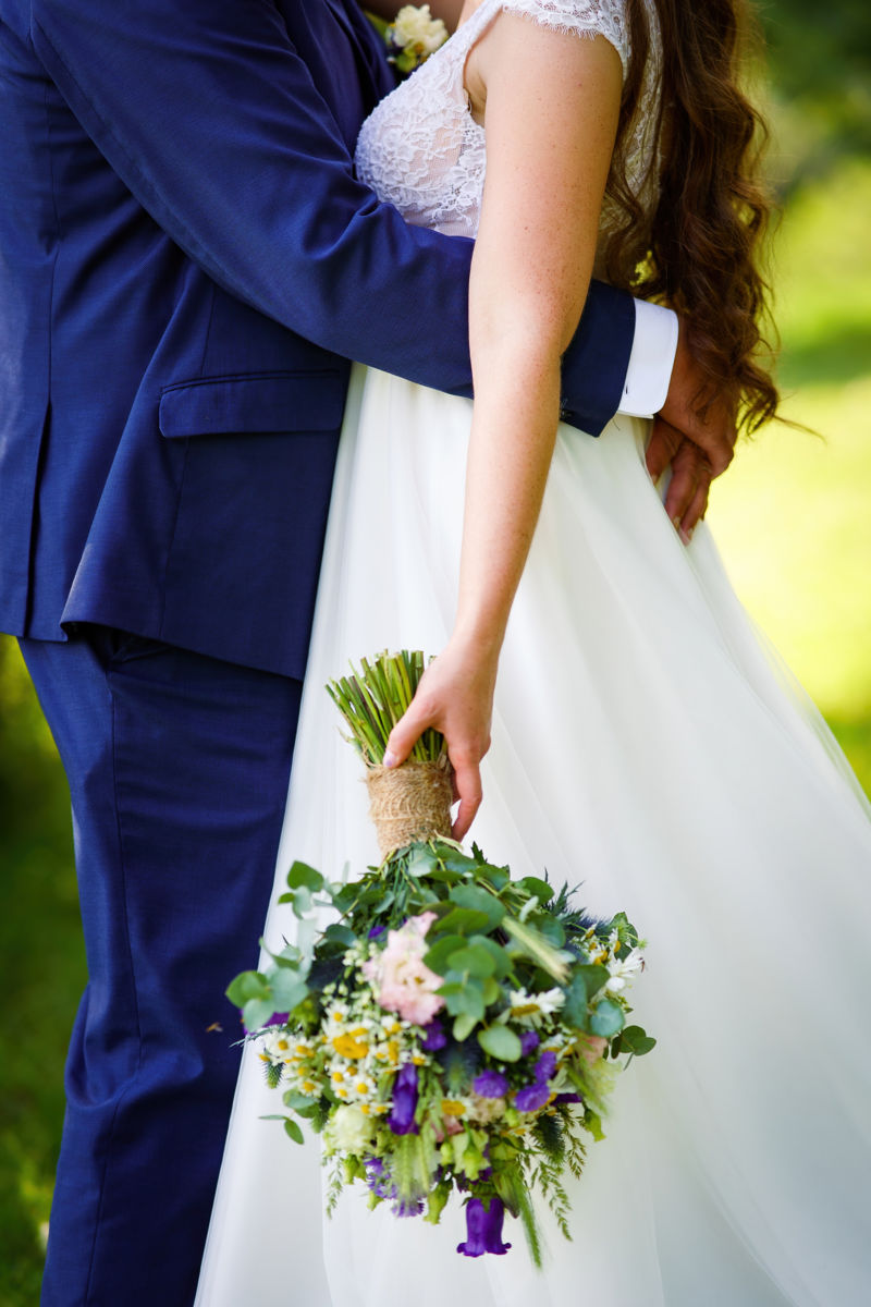 Detail na nevěstu a ženicha, jak se drží a nevěsta drží kytici v ruce