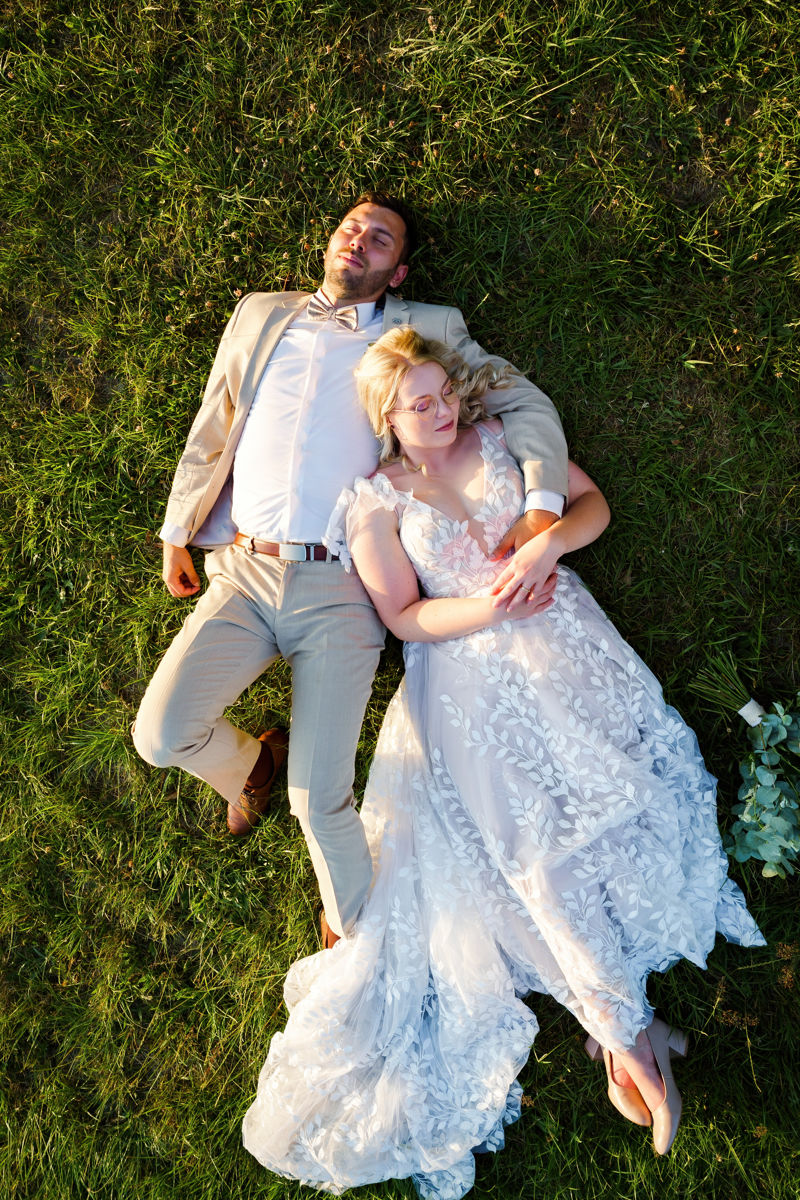 Novomanželé leží v trávě, svatební portrét, svatba Stanský mlýn